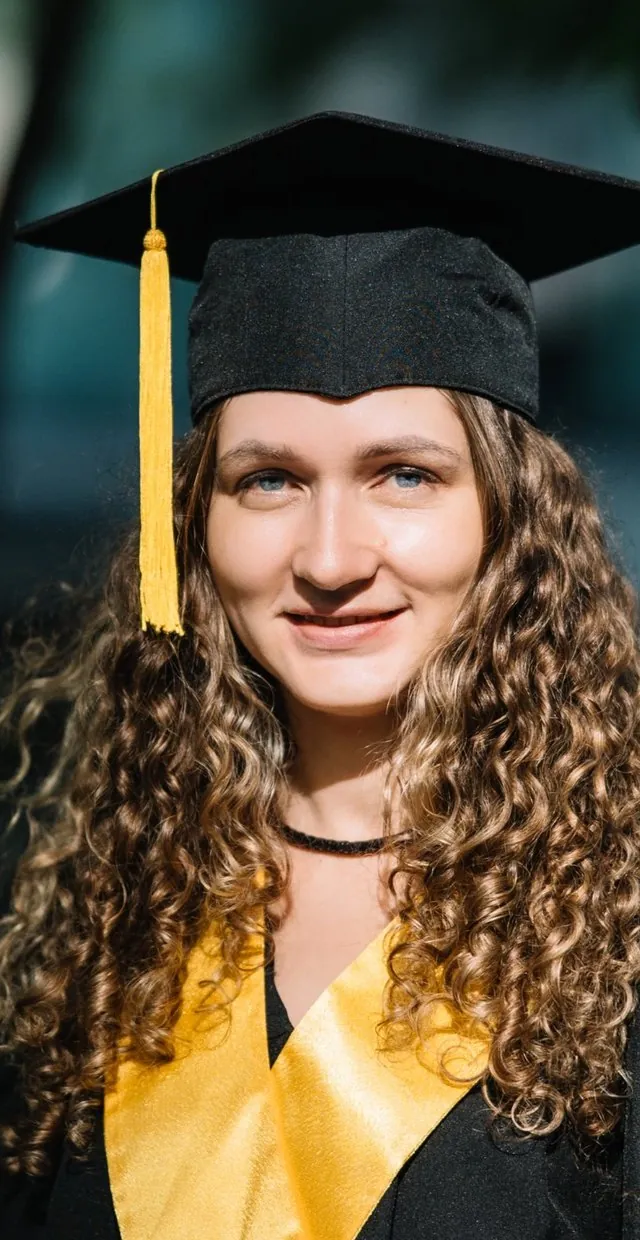 Випускник SET University у шапочці усміхається